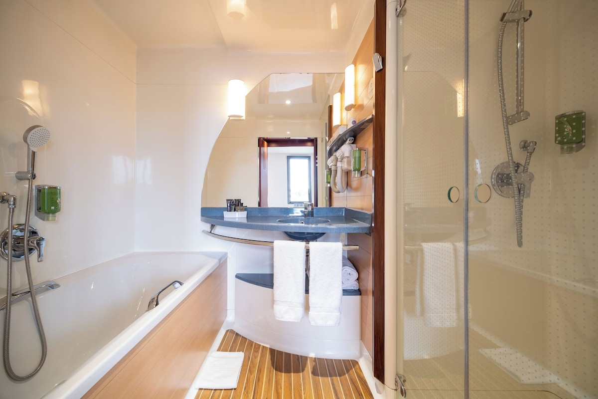 A modern bathroom with a bathtub, shower, and vanity.
