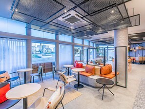 Ein modernes Interieur mit Sitzbereichen, Tischen und großen Fenstern mit Blick auf die Stadt.