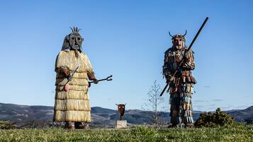 Two individuals in traditional attire standing in a grassy field with a clear sky.