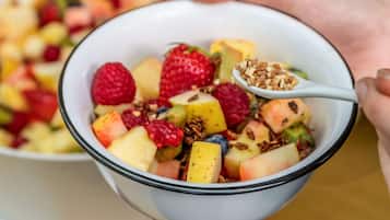 Eine Schüssel Obstsalat mit einem Löffel Granola.