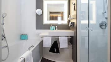 A modern bathroom with a bathtub, a glass-enclosed shower, and a vanity with a mirror.