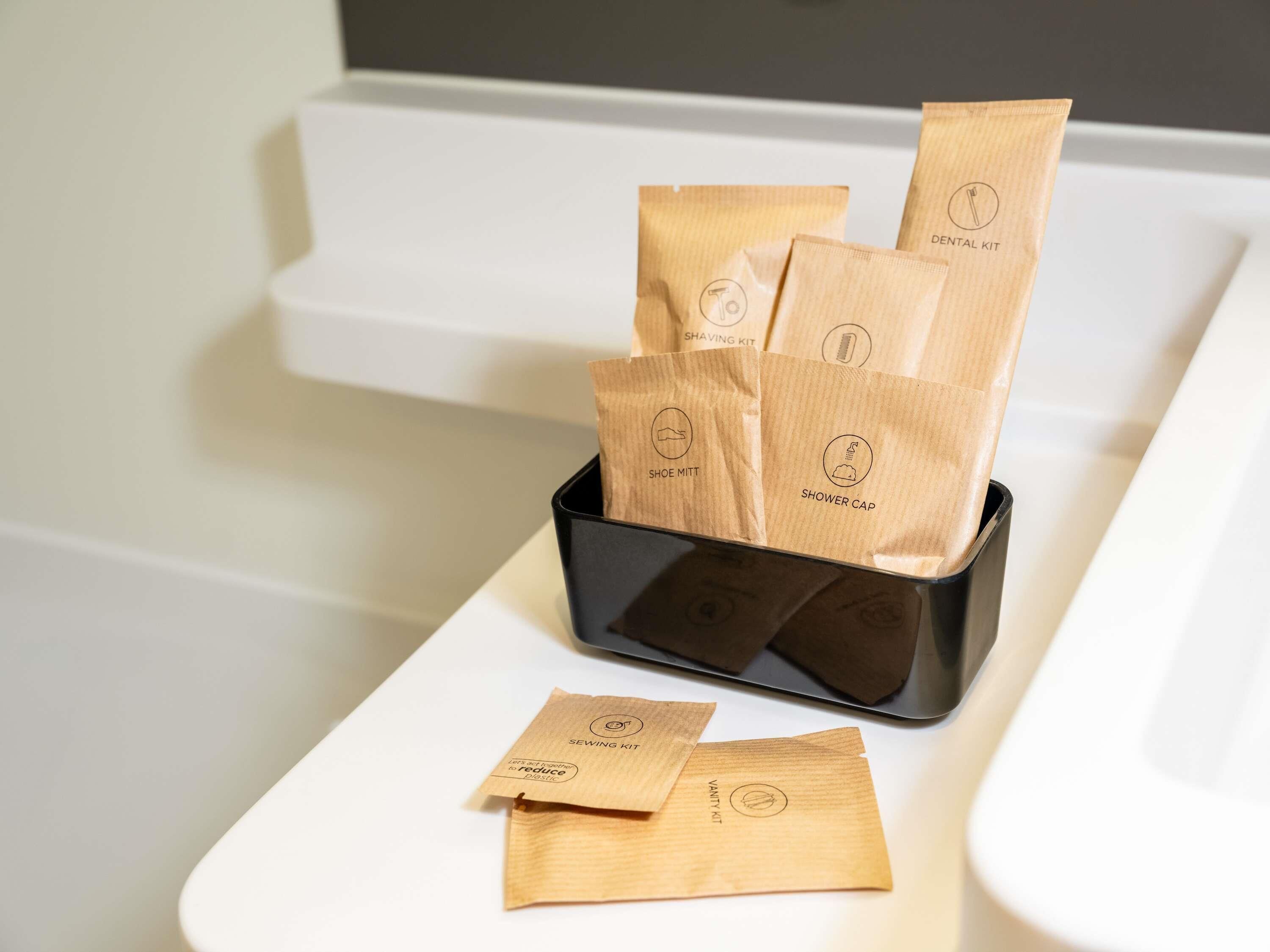 A bathroom with a black tray holding several wooden bags labeled with various toiletries like a shaving kit, shoe mitt, and shower cap.