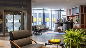 A modern lobby with a reception desk, seating area, and large windows. - Novotel Suites Wien City Donau (Vienna)