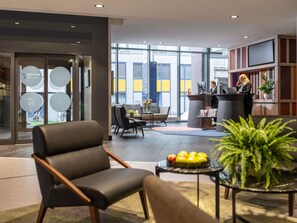 A modern lobby with a reception desk, seating area, and large windows. - Novotel Suites Wien City Donau (Vienna)