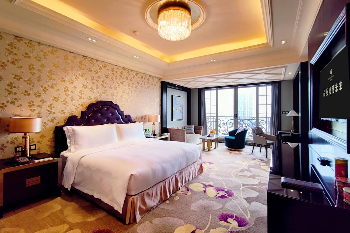 Une chambre d’hôtel avec un grand lit, un bureau, une chaise et un téléviseur.