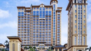 Un hotel grande de varios pisos con un patio central, una fuente y una torre con reloj.