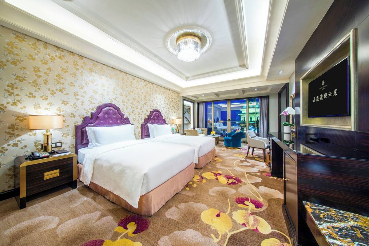 Une chambre d’hôtel avec deux lits, une télévision, un bureau et une vue sur la ville.