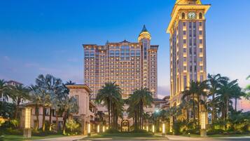 A large hotel with multiple floors, a prominent clock tower, and palm trees in the foreground.
