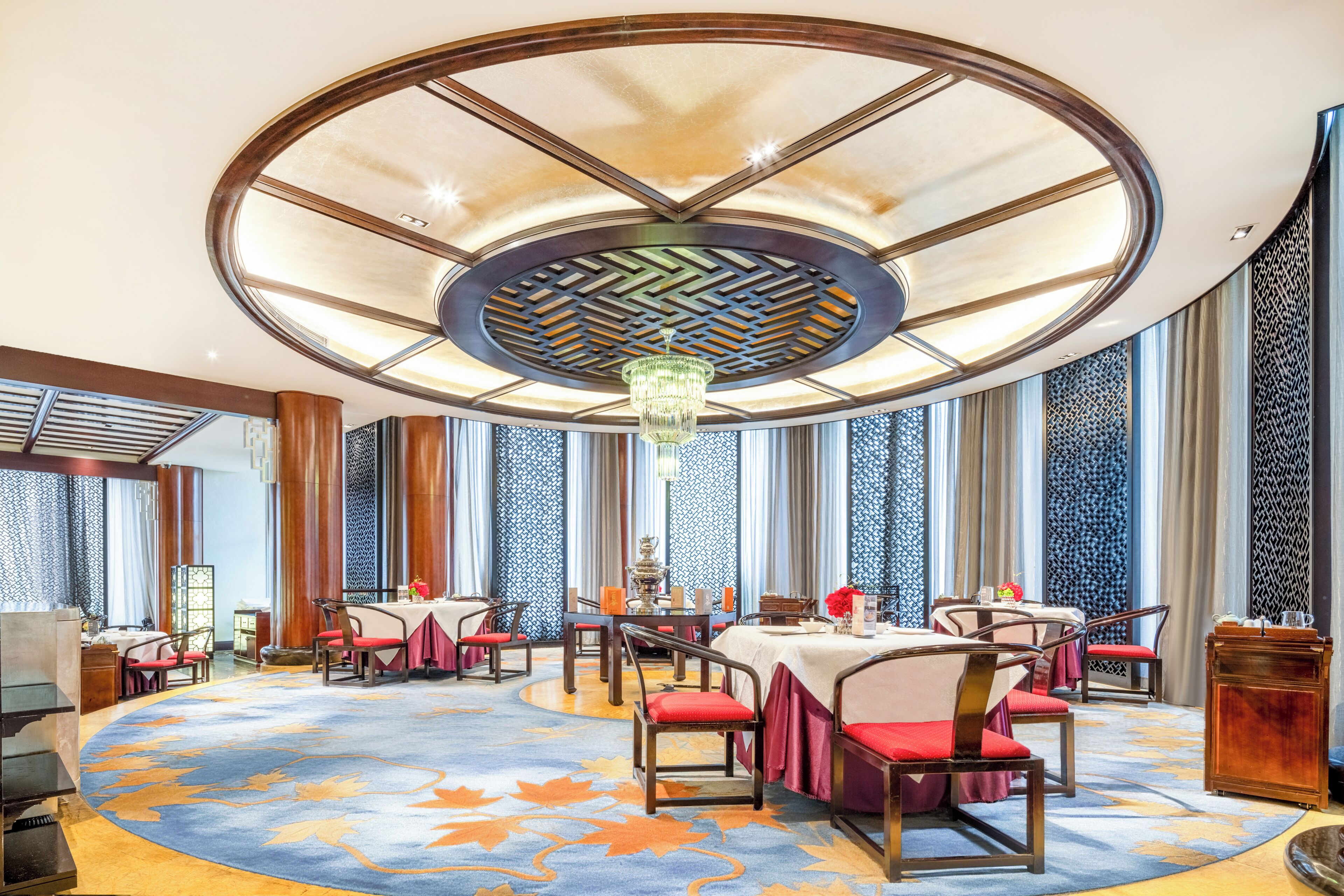 A dining area with round tables, chairs, and a chandelier.