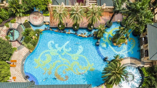 An aerial view of a resort with a large pool featuring a sea turtle design, surrounded by palm trees and various amenities. - Chateau Star River Guangzhou (Guangzhou)