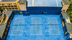 A tennis court with four courts, surrounded by buildings with a blue roof and beige walls. - Chateau Star River Guangzhou (Guangzhou)