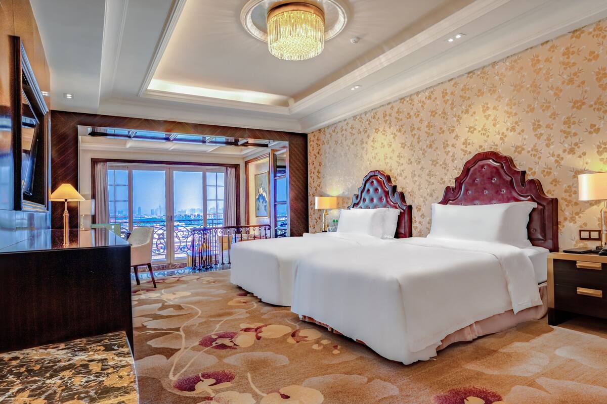 Une chambre d’hôtel avec un grand lit, un bureau et une vue sur la ville.