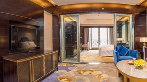 A hotel room with a TV, a sofa, a coffee table, and a bed. - Chateau Star River Guangzhou (Guangzhou)