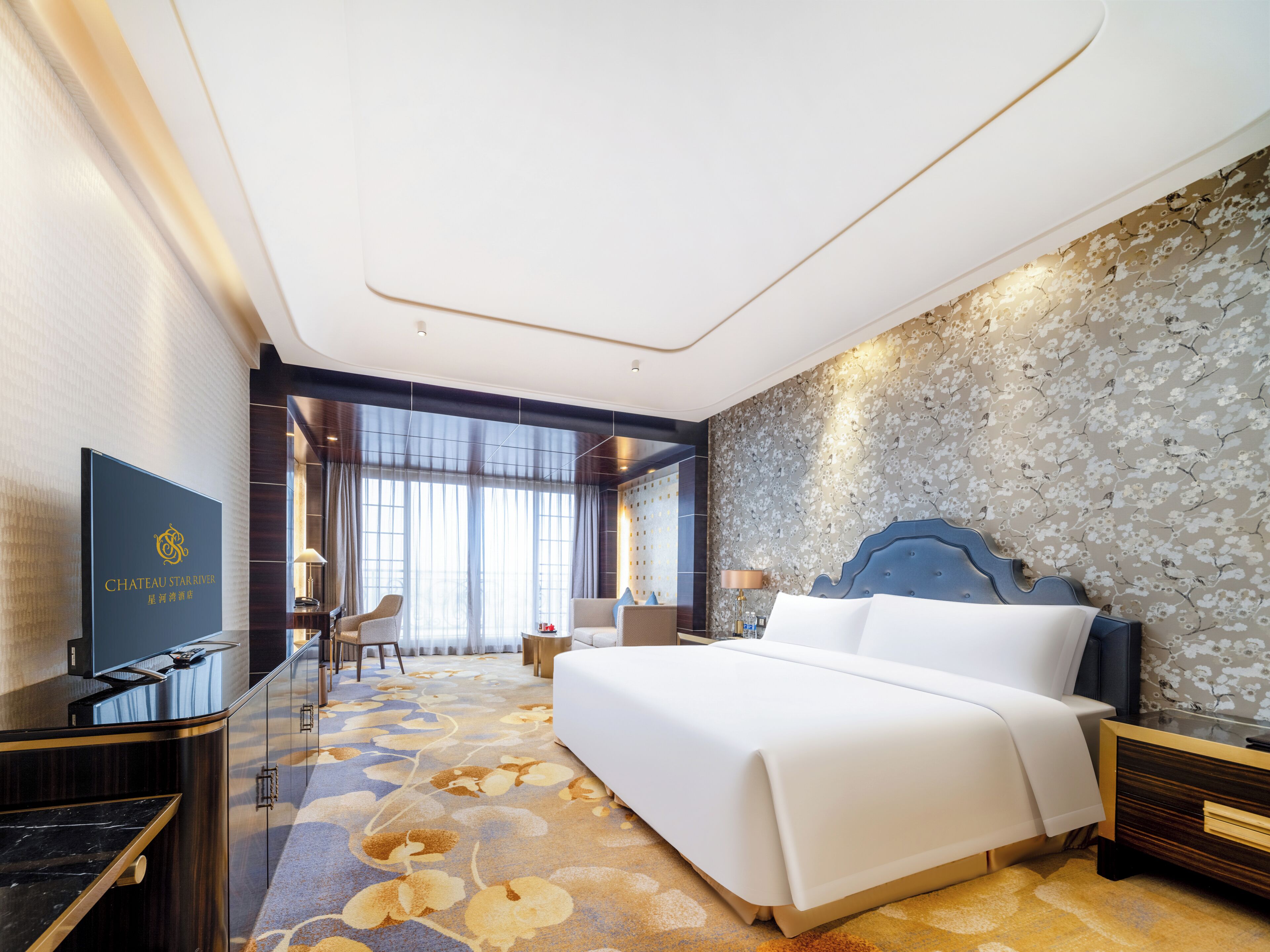 Una habitación de hotel con una cama grande, un escritorio con televisor y una zona de estar con una silla y mesa.