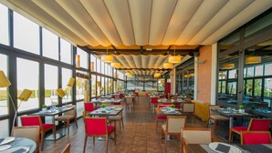A spacious restaurant with high ceilings, large windows, and modern lighting. Tables are neatly arranged with red chairs. - AZZ Salamanca Montalvo (Salamanca)