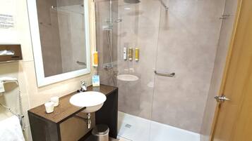 Un baño moderno con ducha envuelta en vidrio, un lavabo y un inodoro.