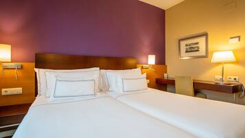 Une chambre d’hôtel avec un grand lit, deux tables de chevet, une chaise et une lampe fixée au mur.