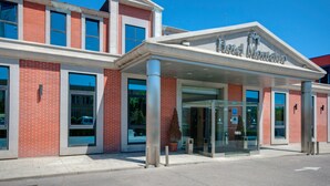 A hotel entrance with a modern design, featuring a prominent name sign, large windows, and a clear sky. - AZZ Salamanca Montalvo (Salamanca)