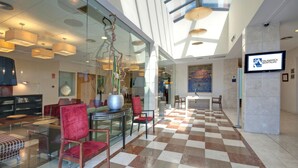 A modern lobby with a checkered floor, glass walls, and contemporary furniture. - AZZ Salamanca Montalvo (Salamanca)