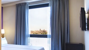 A hotel room with a bed, a TV, and a window with curtains. - AZZ Salamanca Montalvo (Salamanca)