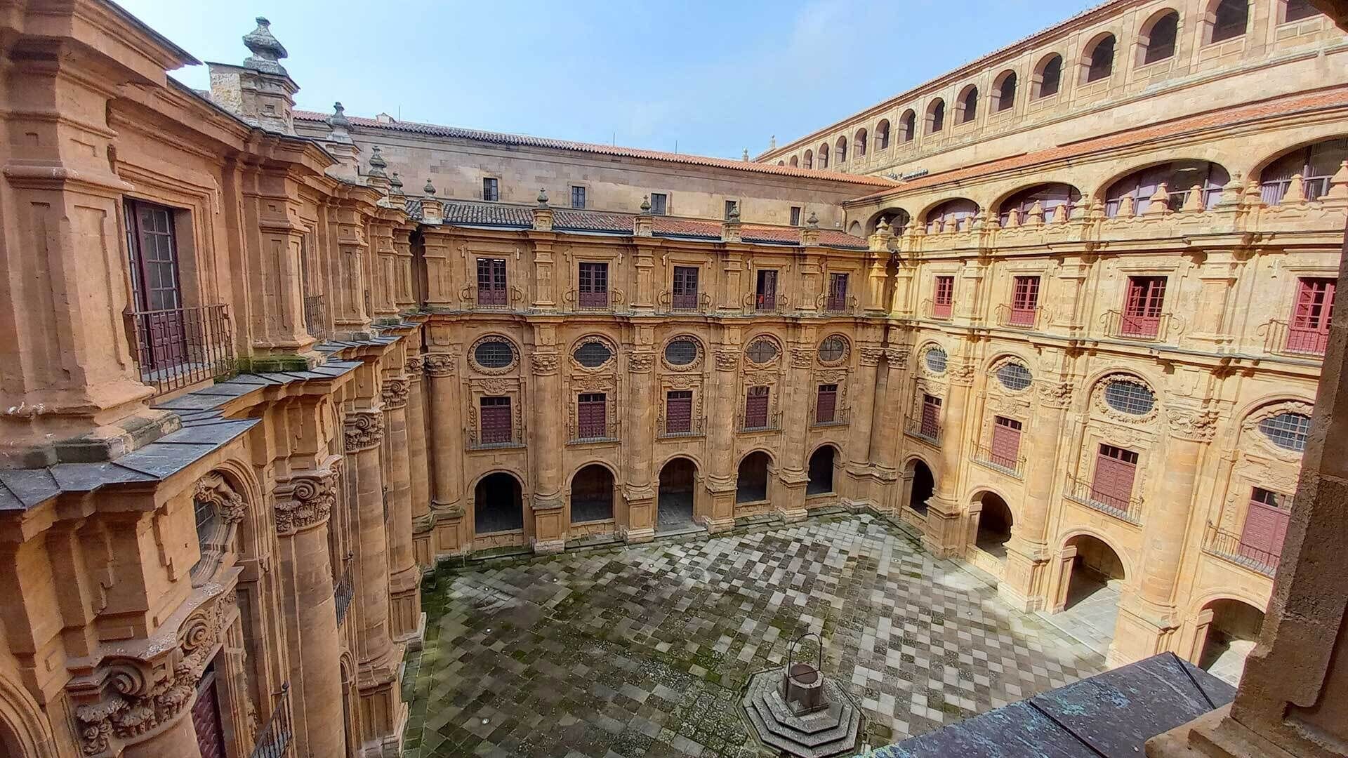 Un patio con una fuente, rodeado de edificios ornamentados con múltiples arcos y balcones.