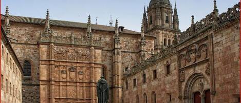 Un edificio histórico con intrincados detalles de piedra, una estatua y un campanario.
