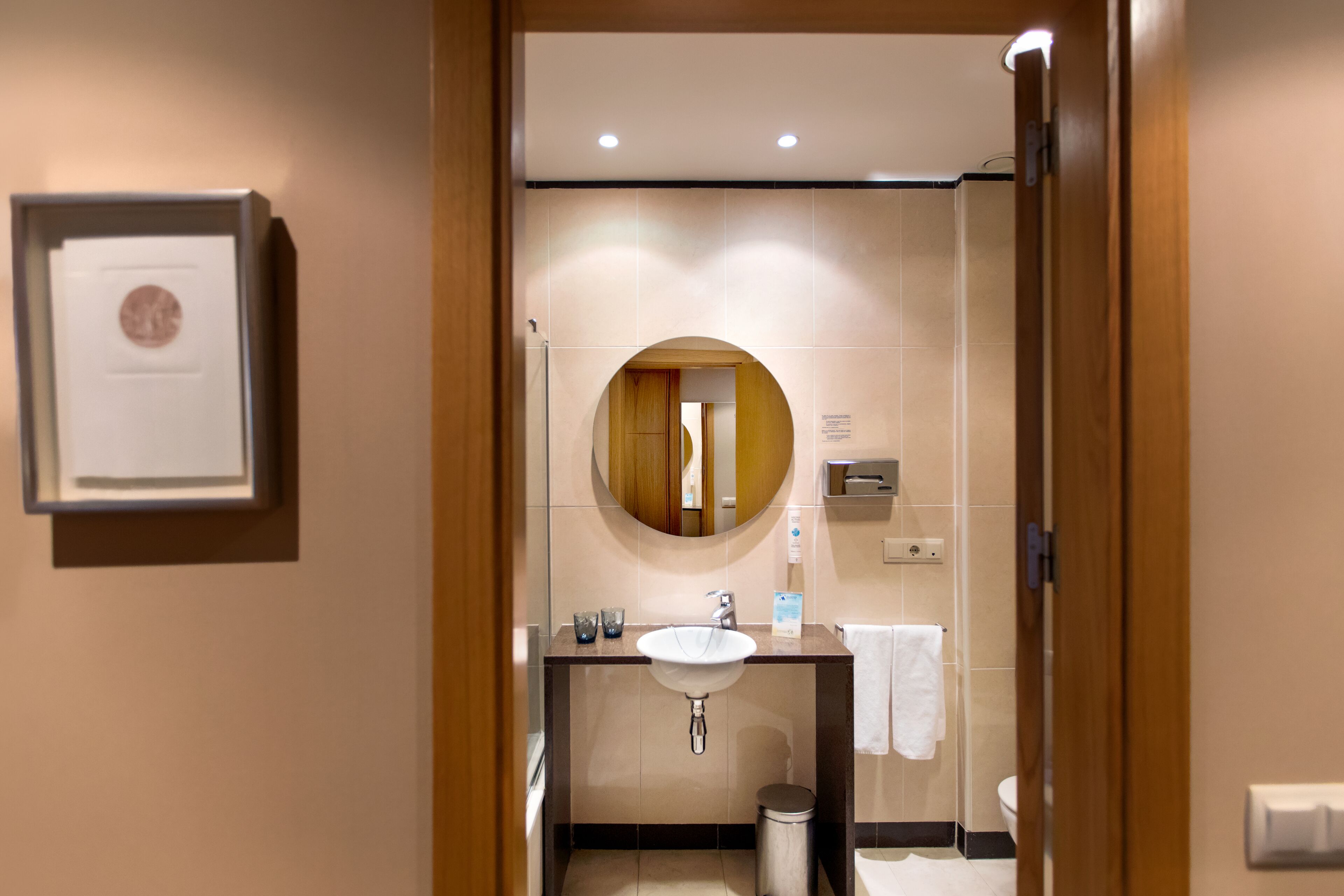 A modern bathroom with a sink, mirror, and toilet.