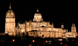 A large, illuminated cathedral with multiple domes and spires, surrounded by other historic buildings. - AZZ Salamanca Montalvo (Salamanca)