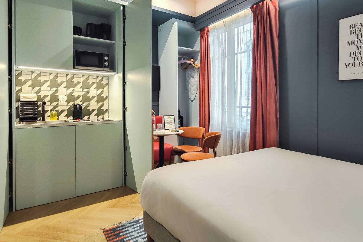 Una habitación de hotel compacta con cama, kitchenette y un pequeño comedor.