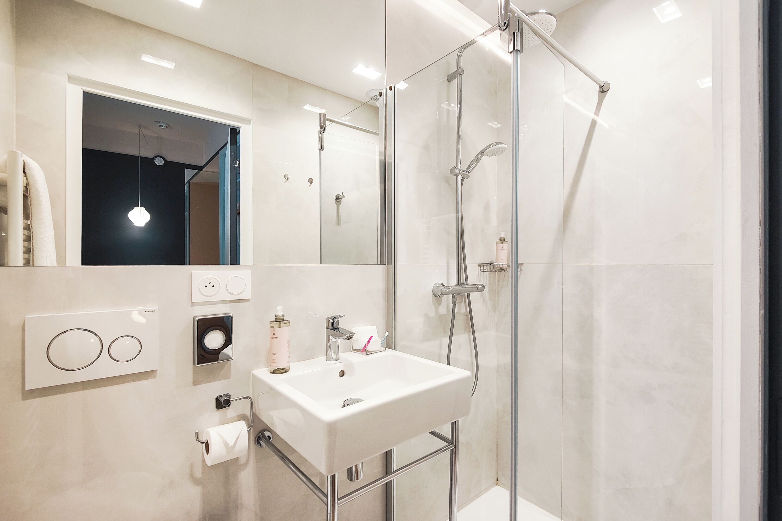 A modern bathroom with a glass-enclosed shower, a white sink, and a mirror above it.
