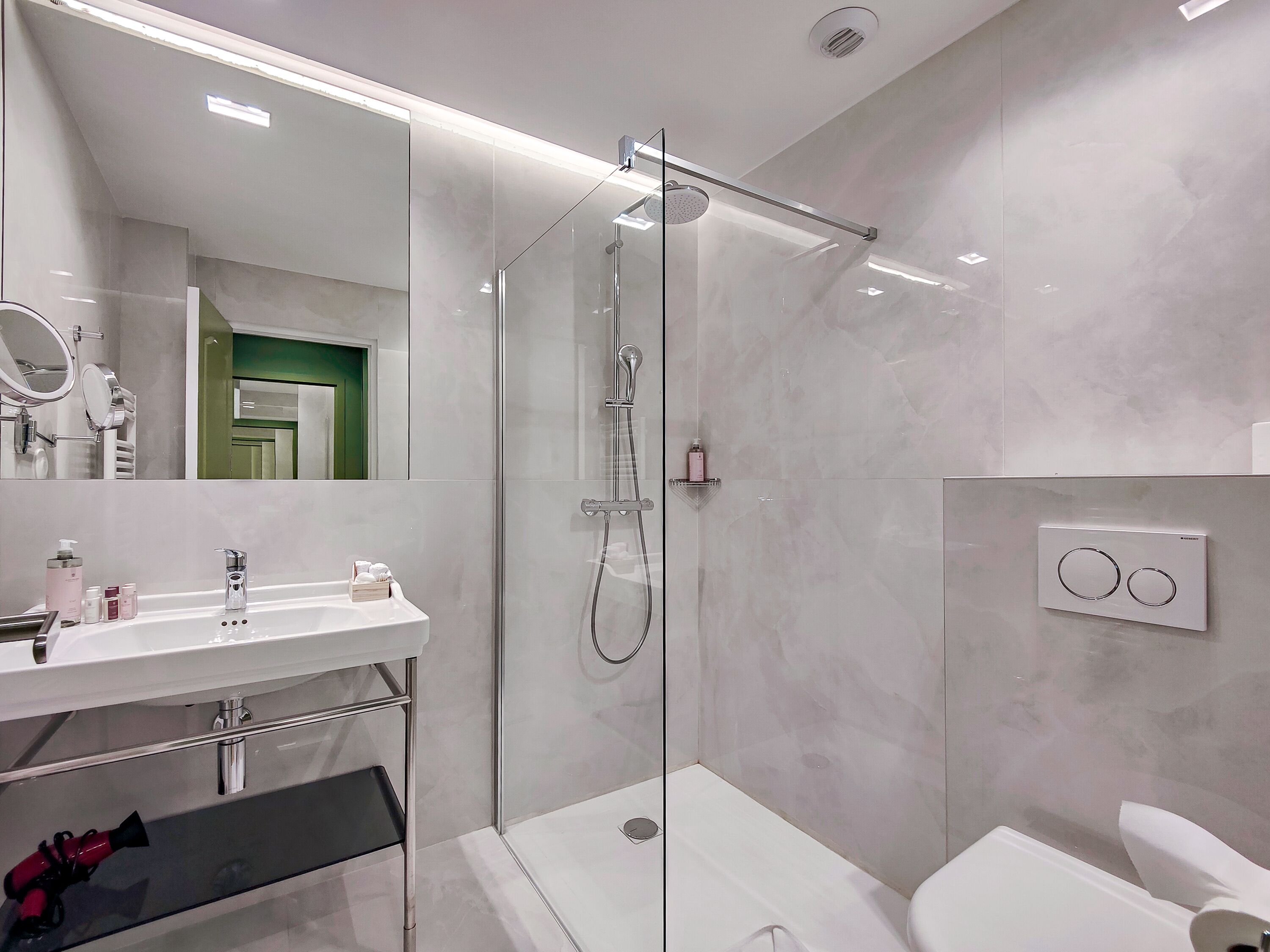 Een moderne badkamer met een douchecabine van glas, een wit wastafelmeubel met spiegel en een toilet.
