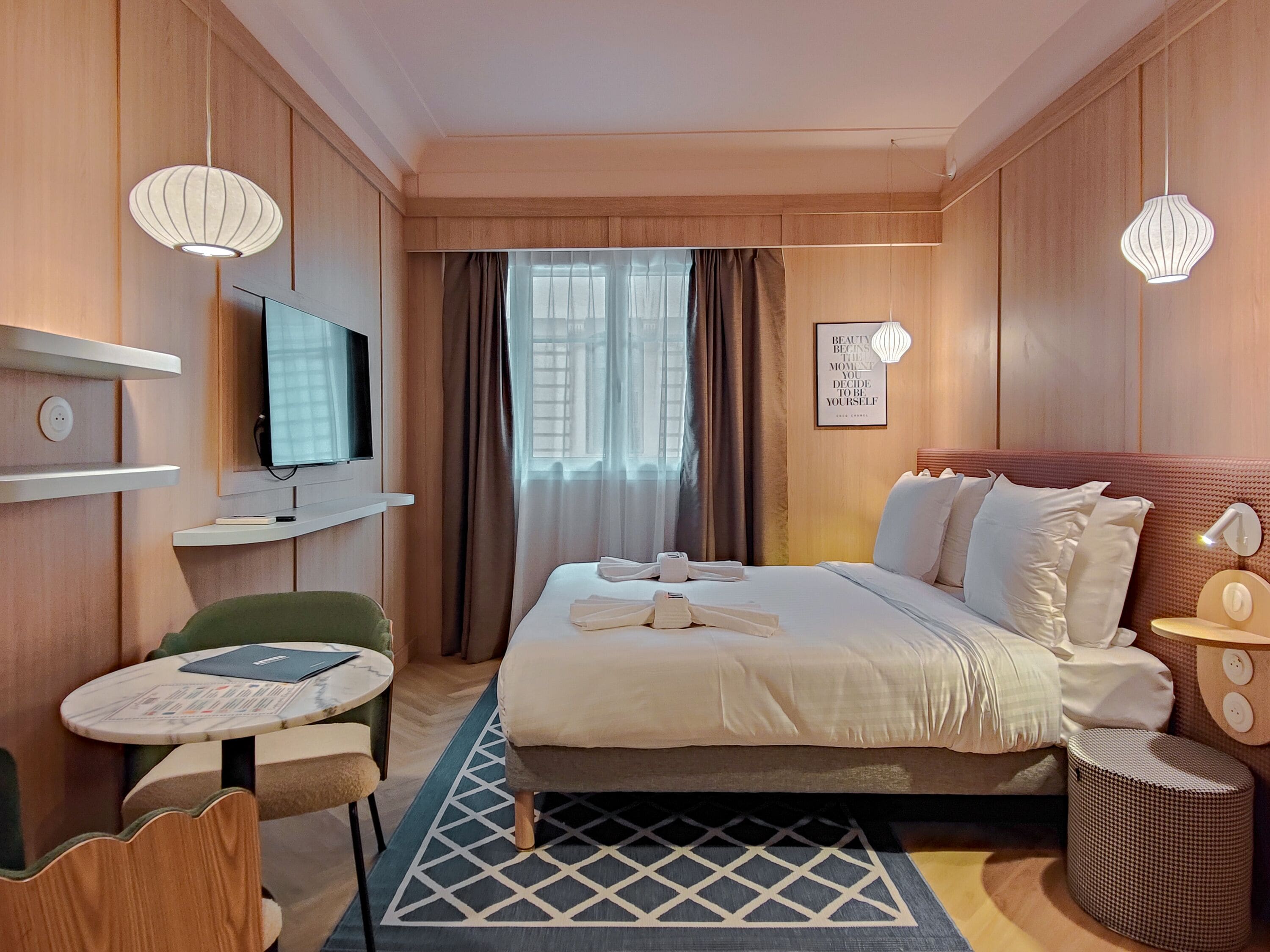 A hotel room with a bed, a TV, a desk, and a chair.