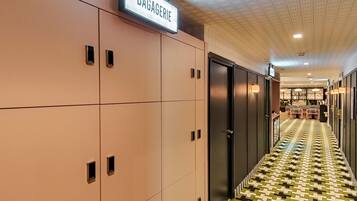 A hallway with lockers, a sign reading "BAGAGERIE," and a patterned floor.