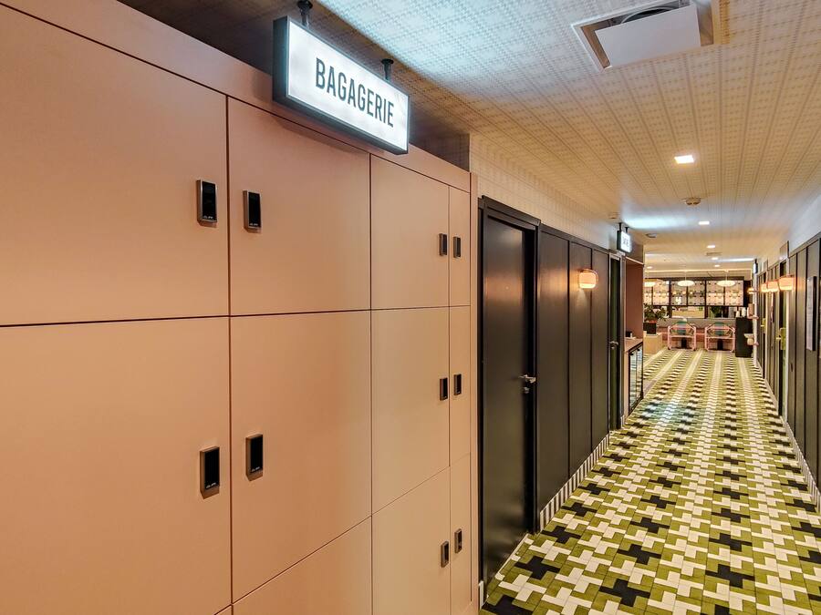A hallway with lockers, a sign reading "BAGAGERIE," and a patterned floor.