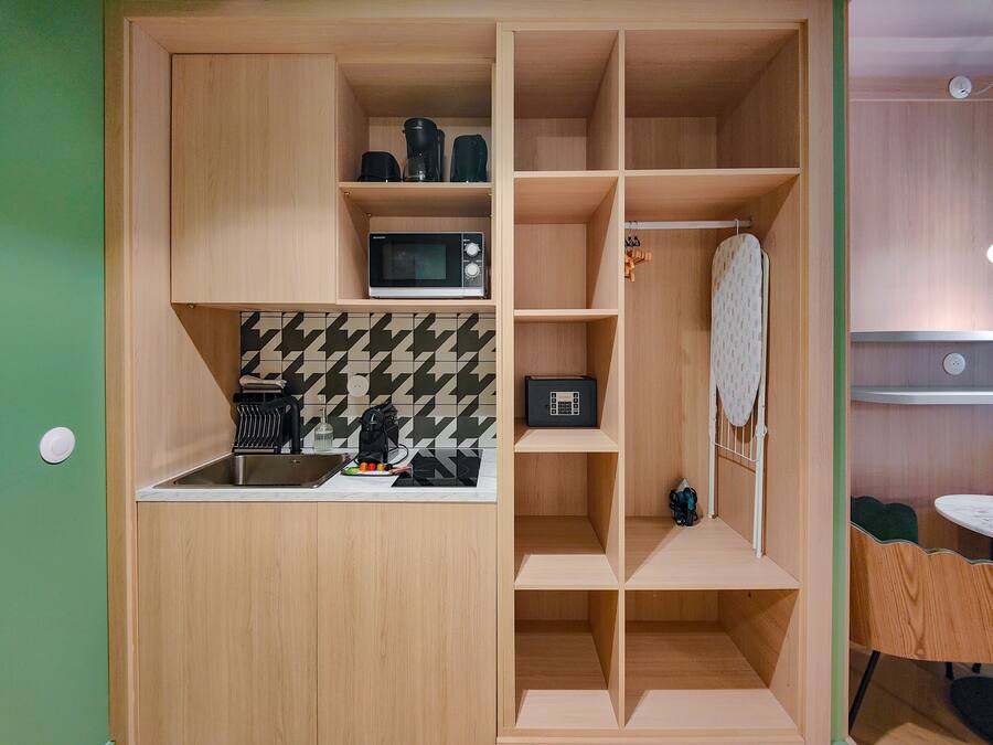 A compact kitchen with a microwave, coffee maker, and a small black device on the countertop.
