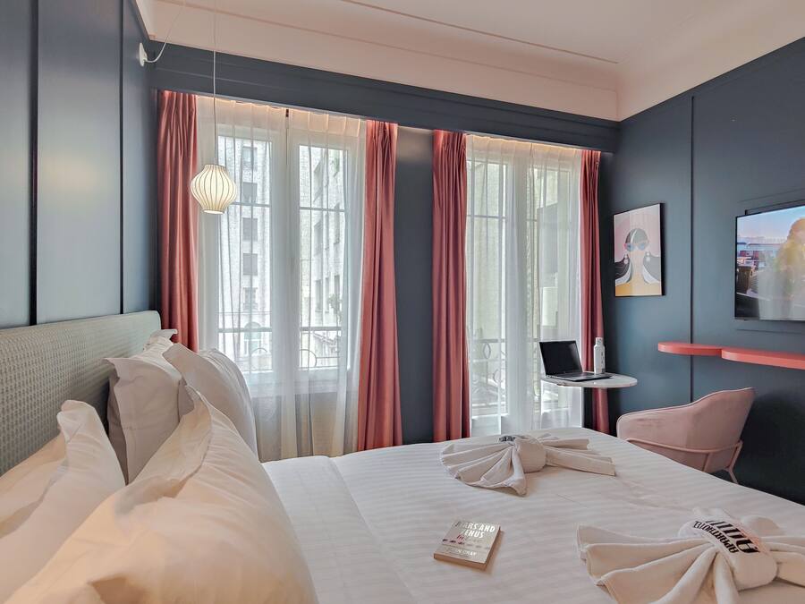 Una habitación de hotel con una cama, un escritorio con una computadora portátil, un televisor y una silla.