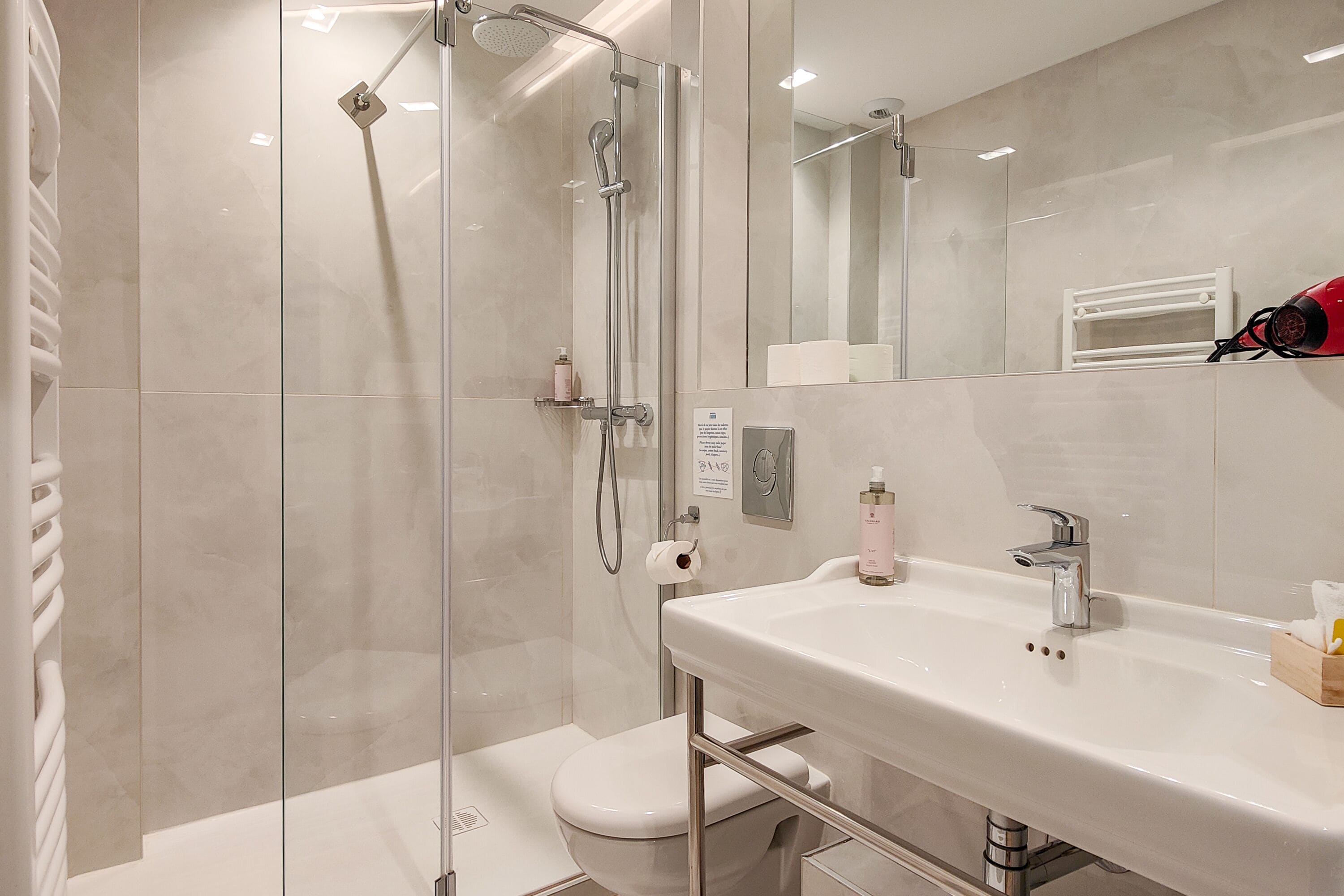 A modern bathroom with a glass-enclosed shower, a white sink, and a toilet.