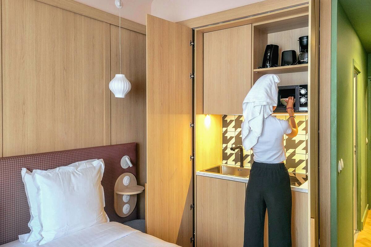 Una habitación de hotel con una cama, un pequeño kitchenette y una puerta verde.