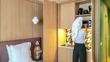Una habitación de hotel con una cama, un pequeño kitchenette y una puerta verde.