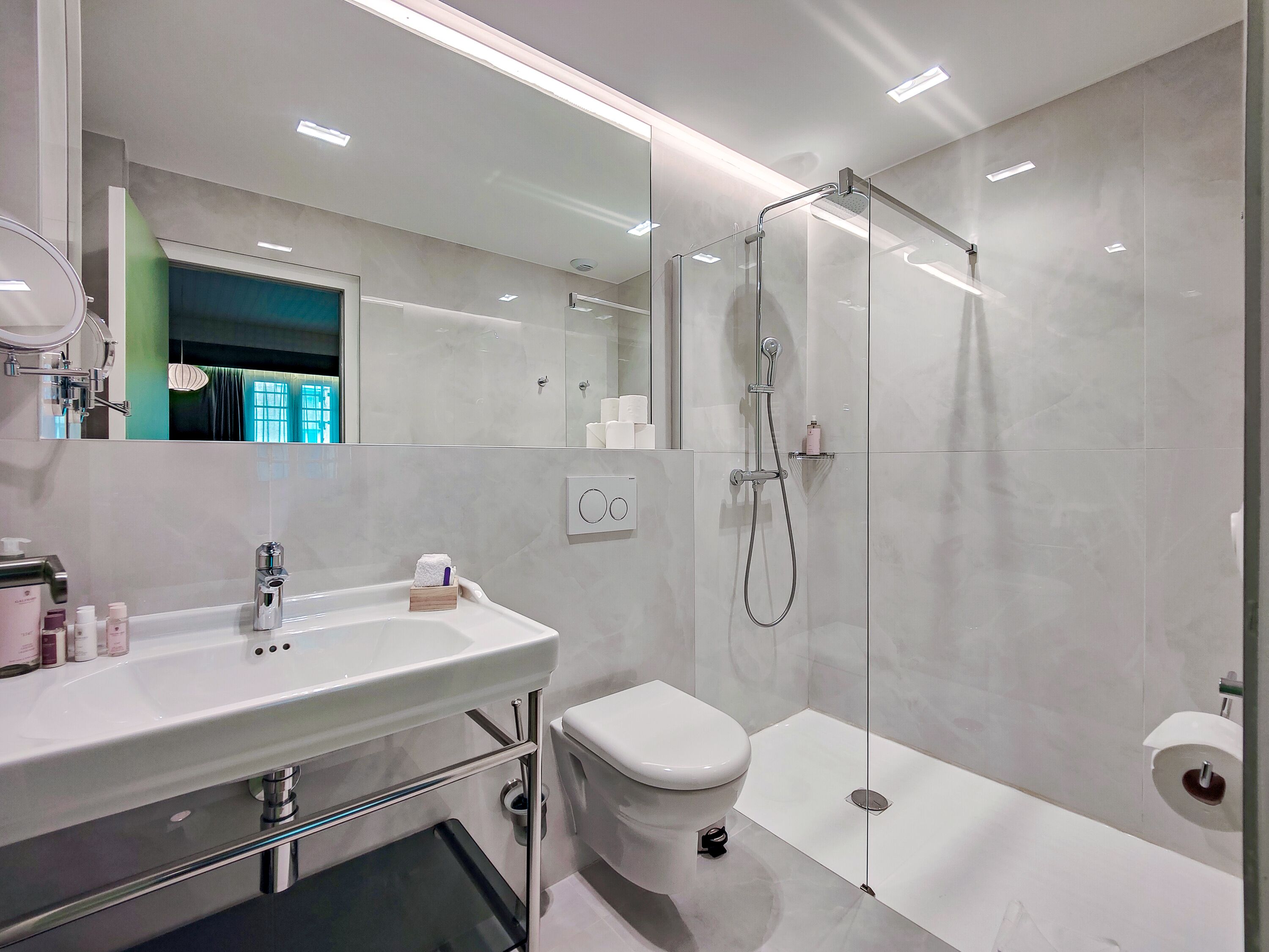 A modern bathroom with a white sink, toilet, and walk-in shower.