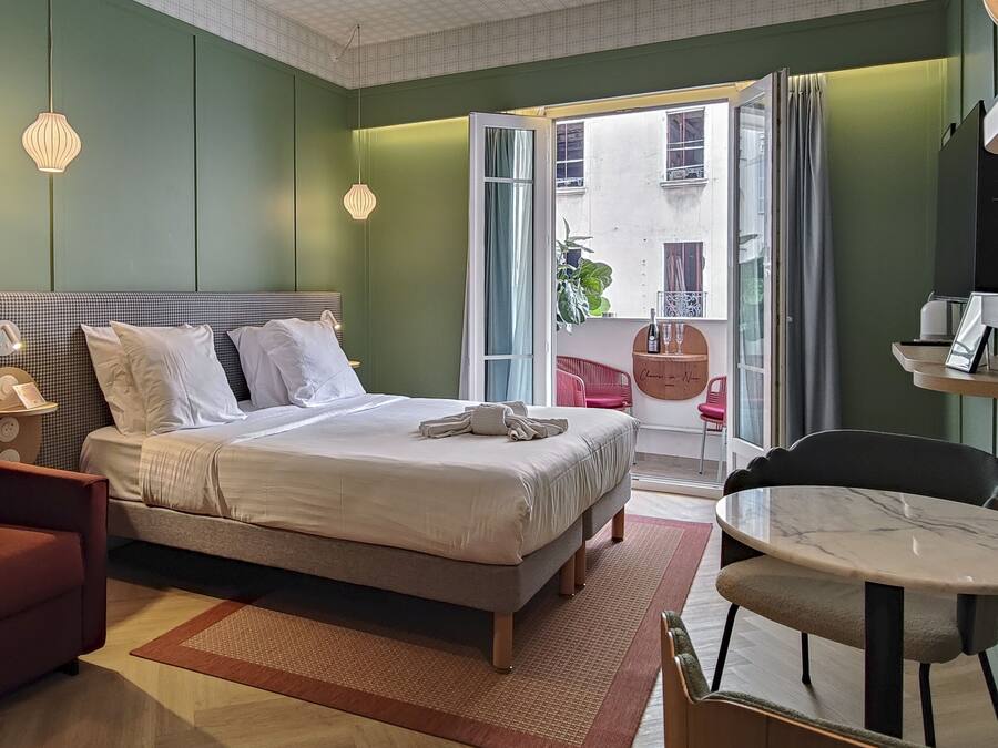 Une chambre d’hôtel moderne équipée d’un lit, d’un bureau, d’une chaise et d’un balcon avec vue.