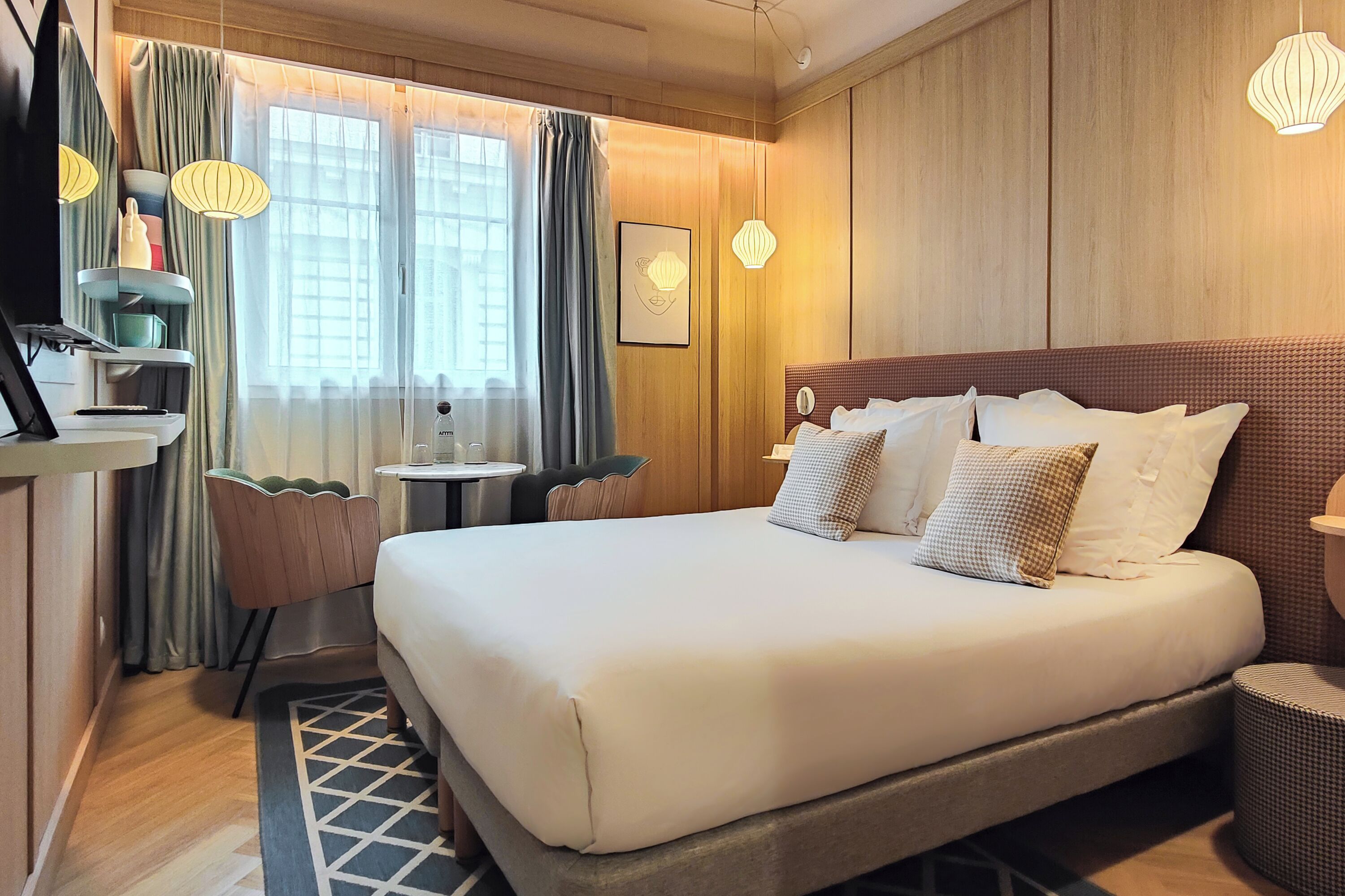 A hotel room with a large bed, a desk, a chair, and a small table.