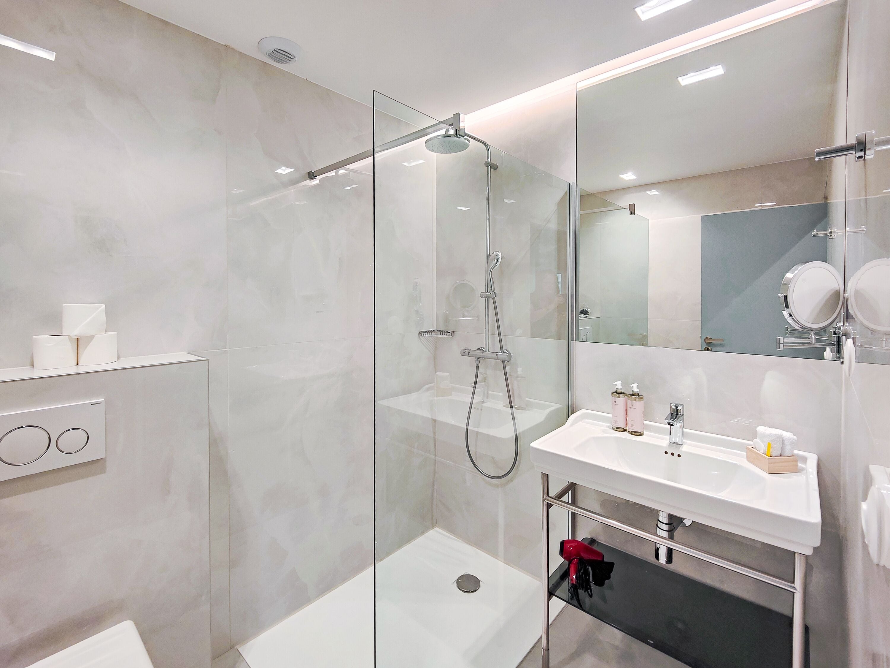 A modern bathroom with a glass-enclosed shower, a white sink, and a large mirror.