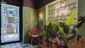 A reception area with a patterned floor, wicker chairs, potted plants, and a neon sign. - Hotel Aparthotel AMMI Nice Lafayette (Nice)