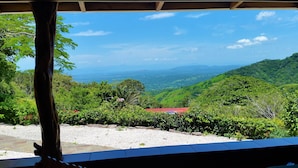 Vista de uma área coberta com vista para um vale exuberante e um litoral distante.