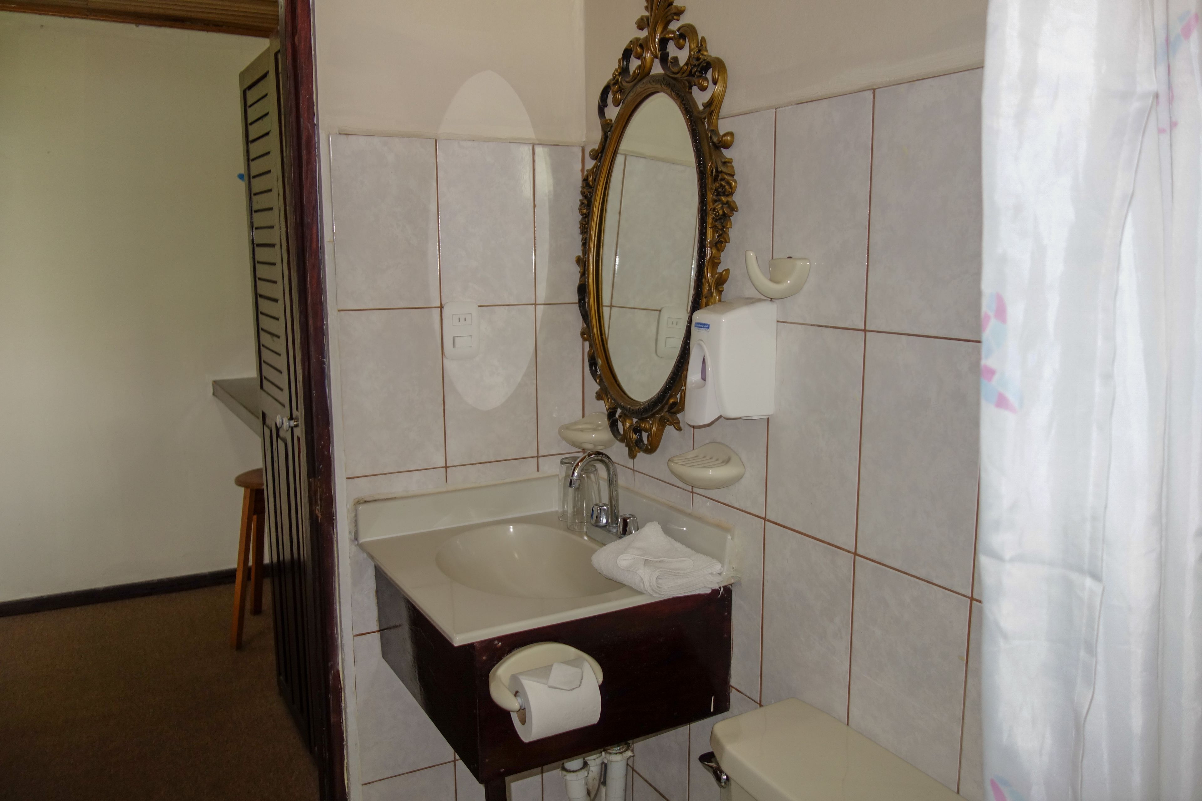 Une salle de bain équipée d’un lavabo, d’un miroir, de toilettes et d’un porte-serviettes.