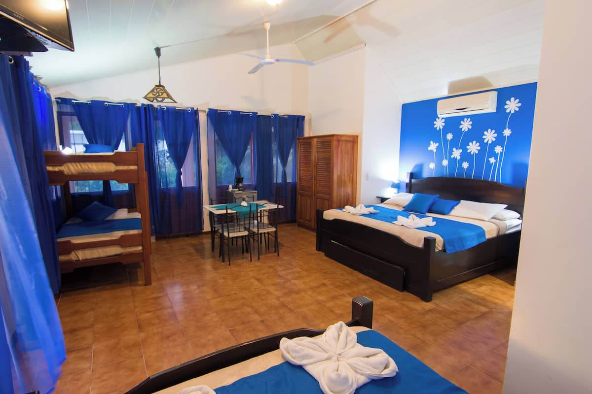 Habitación de hotel con literas, un escritorio con silla, un armario y un ventilador de techo.