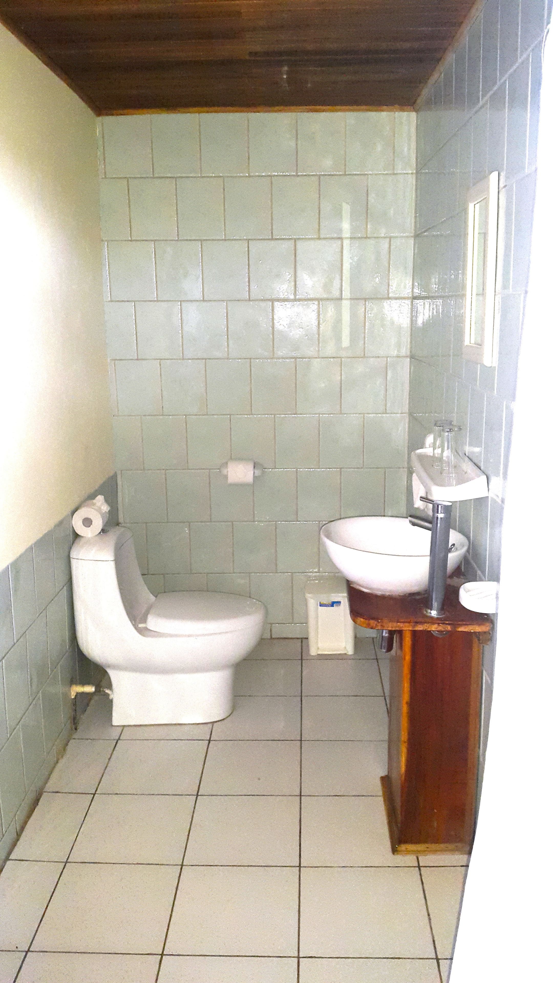 Une petite salle de bain avec des toilettes, un lavabo et des murs carrelés.