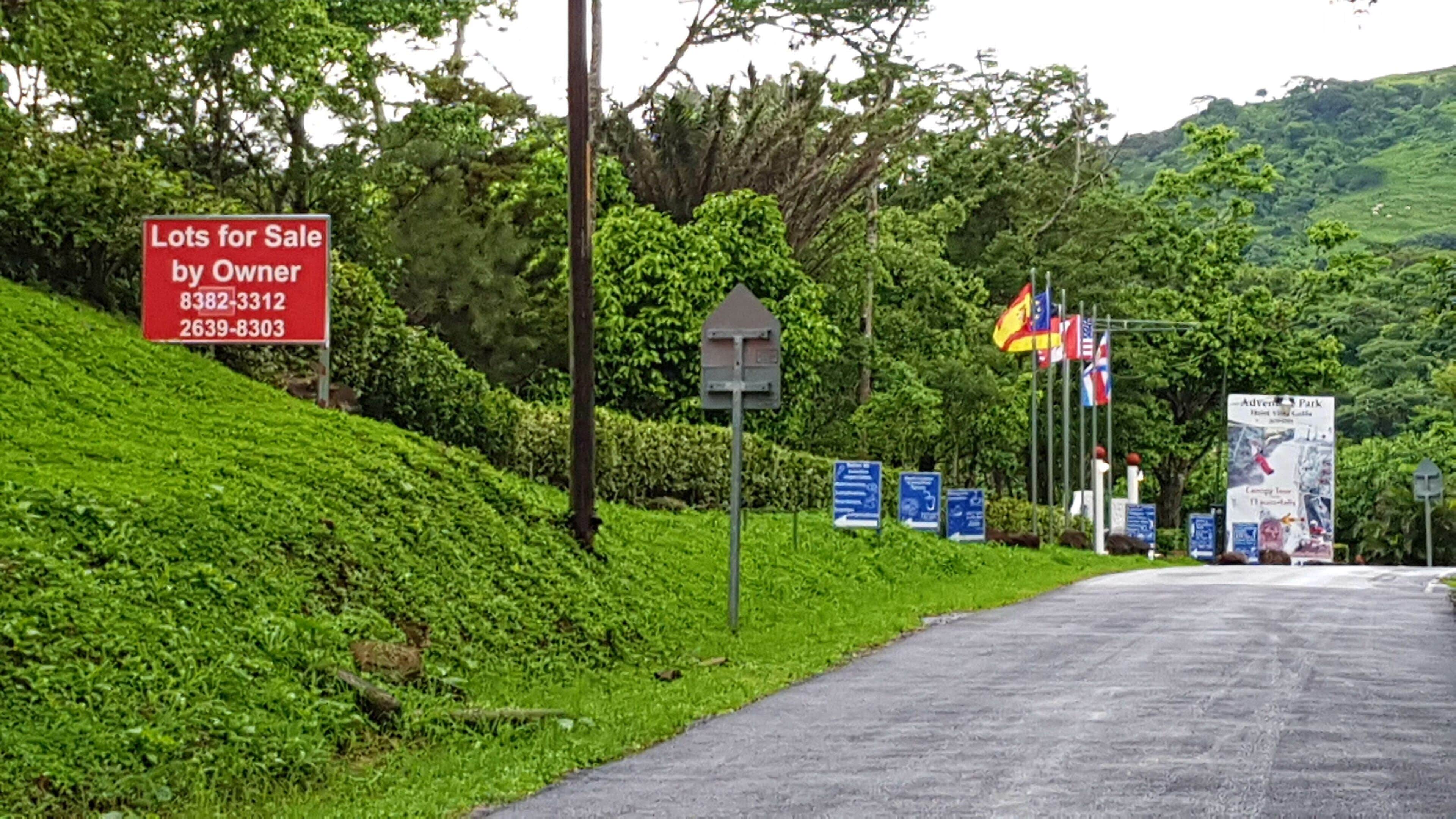 A roadside sign advertising lots for sale by owner with contact numbers.