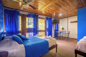 Une chambre avec un lit, un bureau et une chaise, une télévision et une fenêtre avec des rideaux.